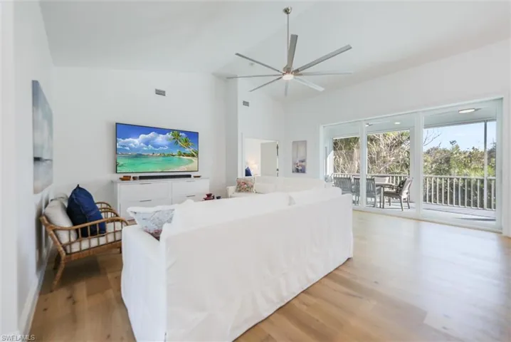 Living room with light hardwood / wood-style flooring, high vaulted ceiling, and ceiling fan