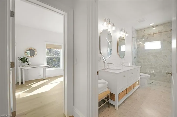 Bathroom with double vanity, marble tiled shower and floors