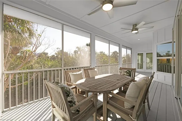 Screened lanai with ceiling fans overlooking tropical landscaping