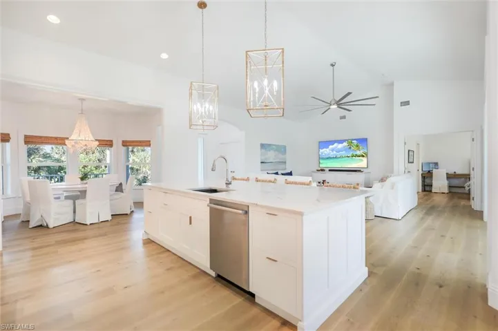 Kitchen featuring a center island with sink, white cabinetry, pendant lighting, and stainless steel dishwasher