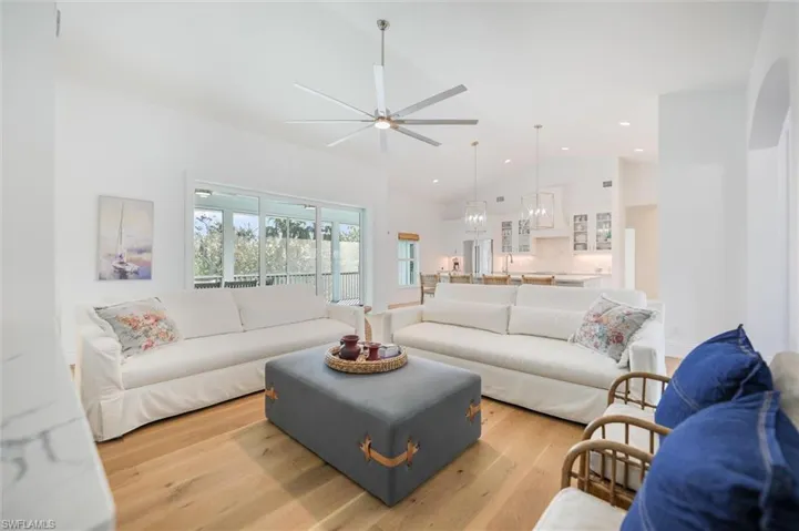 Living room featuring ceiling fan, high vaulted ceiling, and light hardwood / wood-style flooring