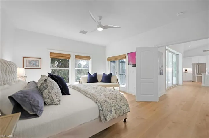 Bedroom with stainless steel refrigerator, ceiling fan, vaulted ceiling, and light wood-type flooring
