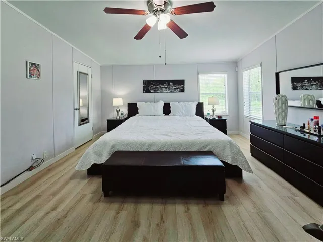 Bedroom with light wood-type flooring, crown molding, and a ceiling fan
