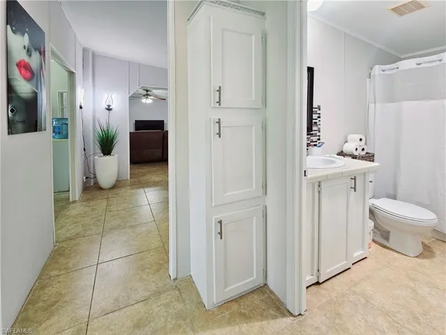 Full bathroom featuring a shower with curtain, ceiling fan, vanity, and light tile patterned floors