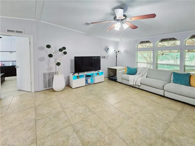 Living room featuring a ceiling fan, ornamental - molding, and light tile patterned flooring