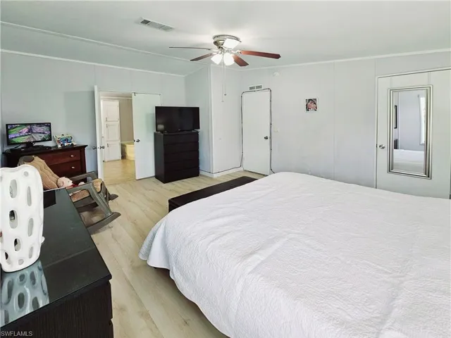 Bedroom with light wood-type flooring, crown molding, and a ceiling fan