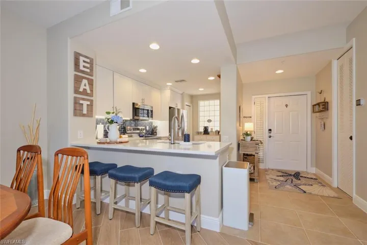 Kitchen featuring kitchen peninsula, stainless steel appliances, white cabinets, and tasteful backsplash