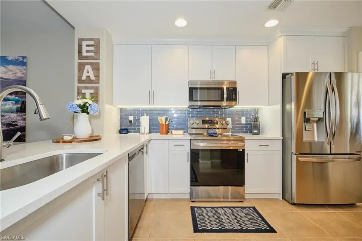 Kitchen featuring appliances with stainless steel finishes, light tile patterned floors, white cabinetry, and sink