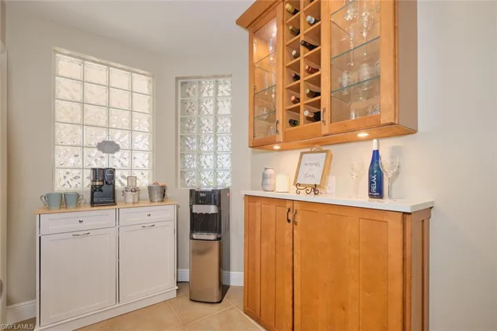 Bar with white cabinets and light tile patterned floors