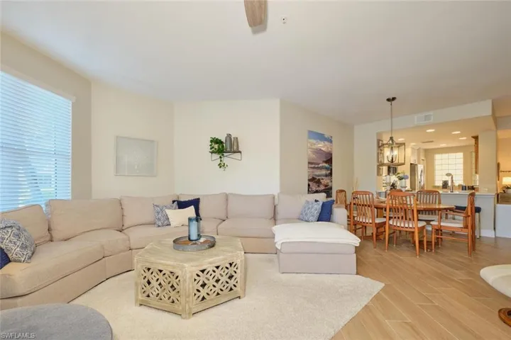 Living room with wood-type flooring and ceiling fan with notable chandelier