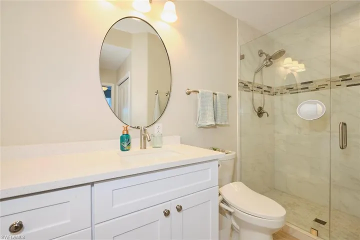 Bathroom with vanity, a shower with shower door, and toilet