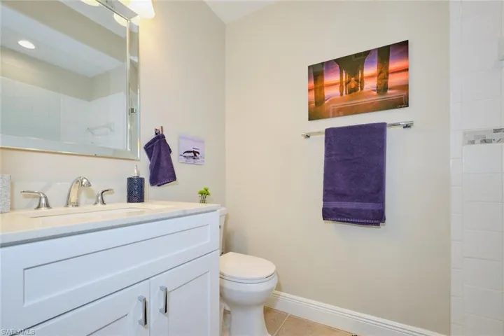 Bathroom with a tile shower, tile patterned flooring, vanity, and toilet