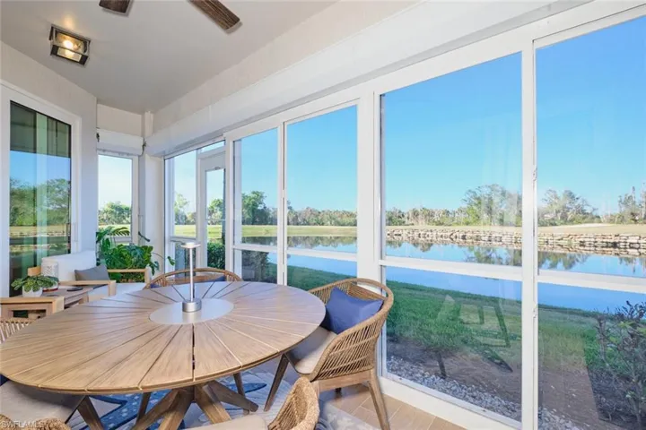 Sunroom / solarium with ceiling fan and a water view