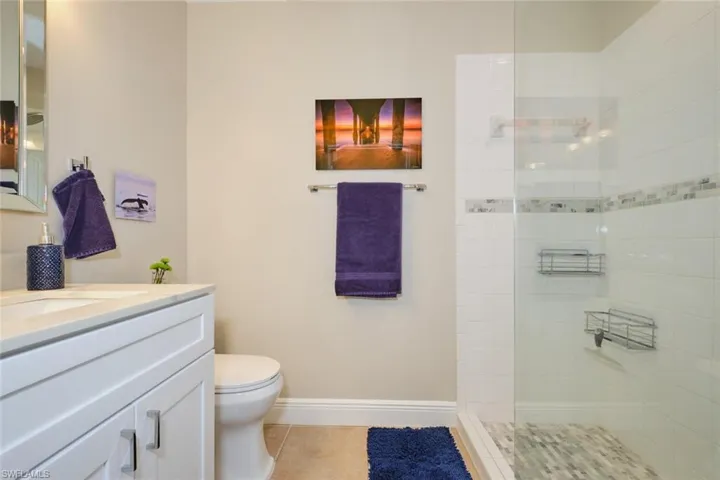 Bathroom featuring tile patterned flooring, vanity, toilet, and tiled shower