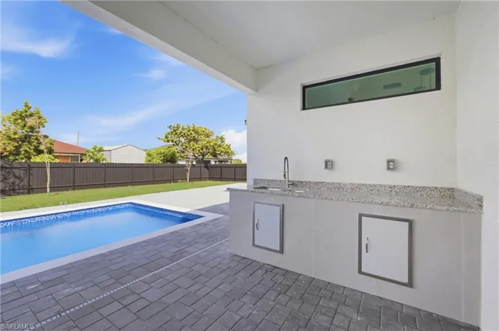 View of pool featuring a fenced backyard, patio surround, and exterior kitchen