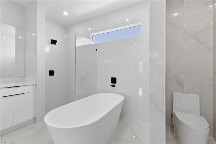Full bath featuring a freestanding bath, recessed lighting, tile walls, and vanity