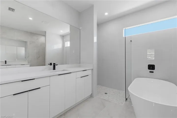 Full bathroom featuring vanity, walk in shower, a soaking tub, and recessed lighting