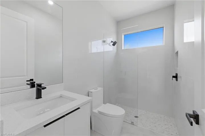Full bath featuring vanity, walk in shower, and tile walls
