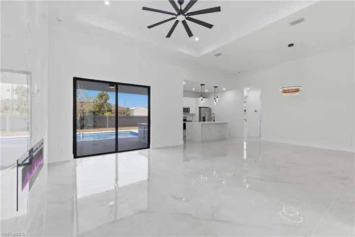 Unfurnished living room with recessed lighting, light marble finish flooring, ceiling fan, and a raised ceiling