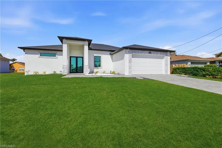 Prairie-style house featuring concrete driveway, a front lawn, and stucco siding