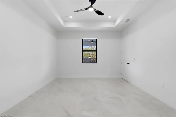 Empty room featuring a tray ceiling, a ceiling fan, and recessed lighting