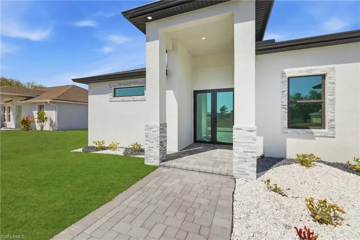 Entrance to property with french doors, stucco siding, and a yard