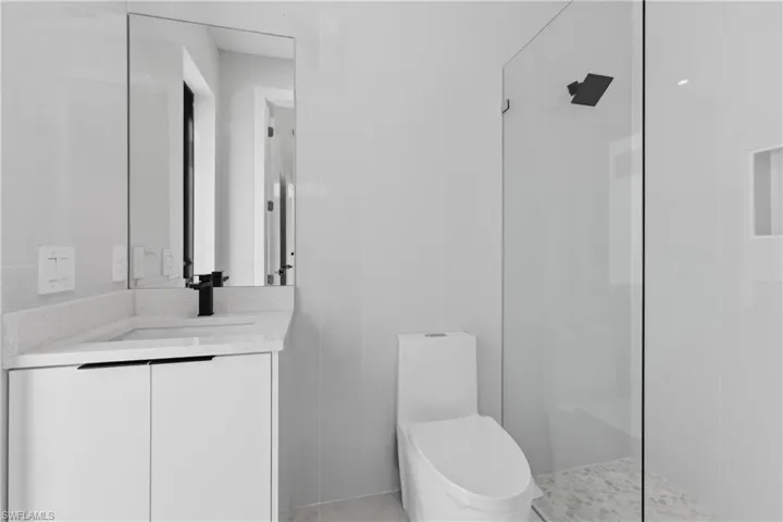 Full bath featuring vanity, walk in shower, and tile walls
