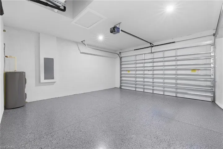 Garage with water heater, a garage door opener, and electric panel