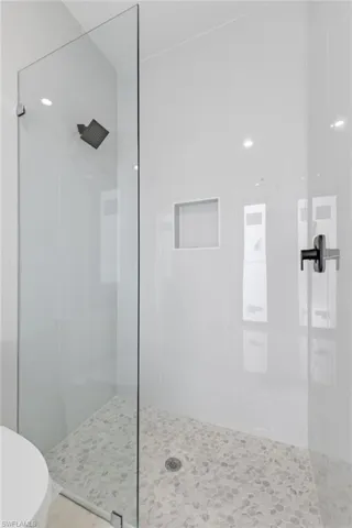 Full bathroom featuring tiled shower and toilet