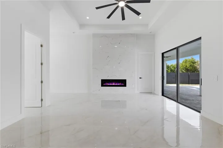 Unfurnished living room with light marble finish flooring, a fireplace, a ceiling fan, a high ceiling, and recessed lighting