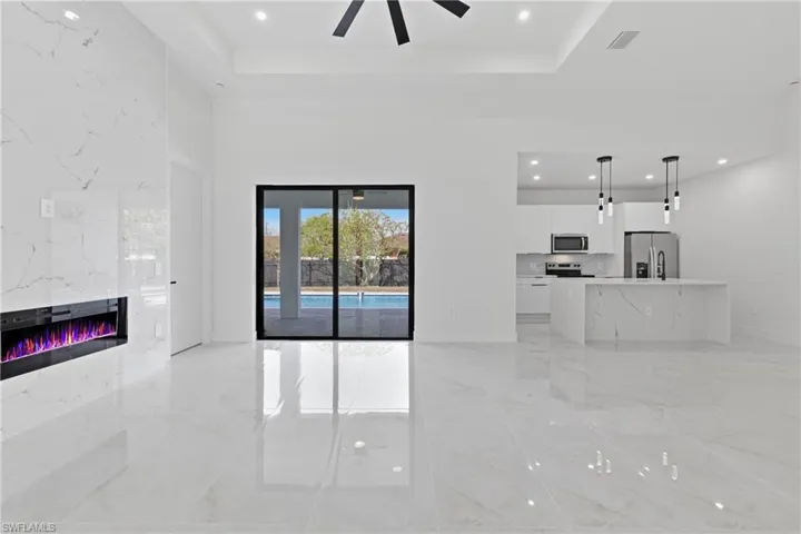 Unfurnished living room with recessed lighting, a raised ceiling, a high end fireplace, ceiling fan, and light marble finish flooring