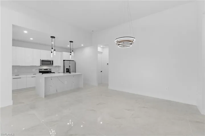 Kitchen featuring white cabinets, pendant lighting, a center island, stainless steel appliances, and modern cabinets