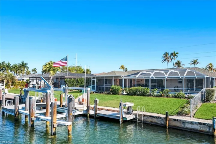 Dock area featuring boat lift, a water view, a sunroom, and glass enclosure