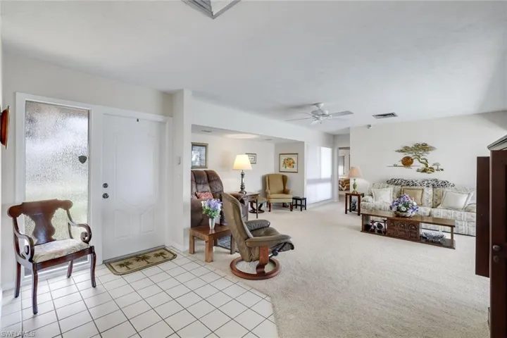 Foyer entrance featuring light colored carpet, a ceiling fan, plenty of natural light, and light tile patterned flooring