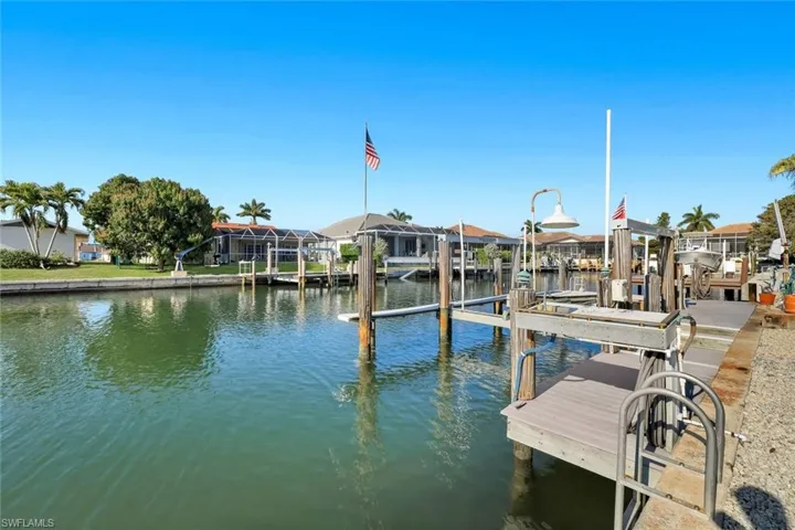 Dock area featuring a water view, boat lift, and a residential view