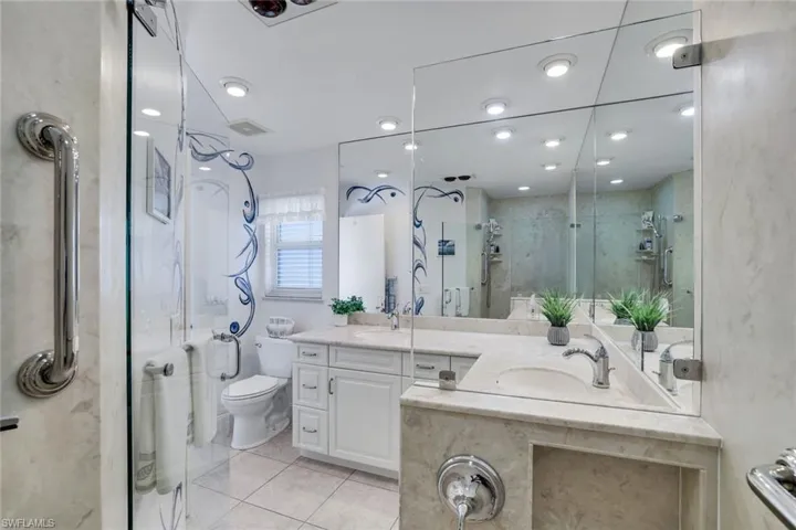 Bathroom with two vanities, a marble finish shower, and light tile patterned flooring