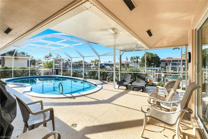 Outdoor pool with glass enclosure, a patio, a sunroom, and boat lift