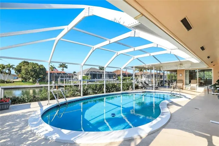 Swimming pool with glass enclosure, a patio area, and a sunroom