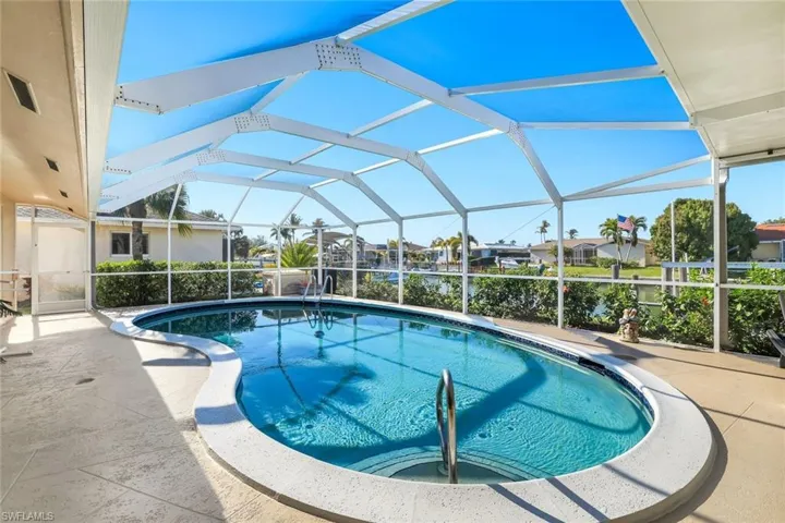 Swimming pool featuring glass enclosure, a sunroom, and a patio area