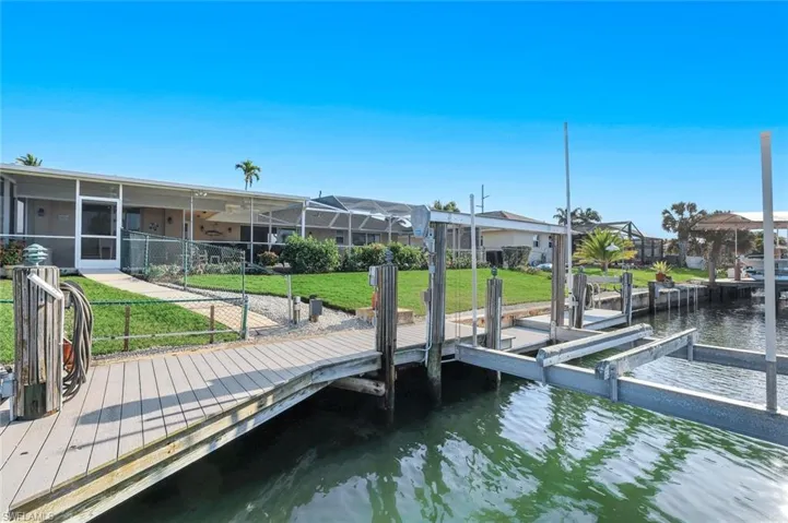 Dock area featuring a water view, a sunroom, glass enclosure, and boat lift