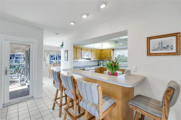 Kitchen featuring light countertops, a breakfast bar, white appliances, a peninsula, and light tile patterned floors