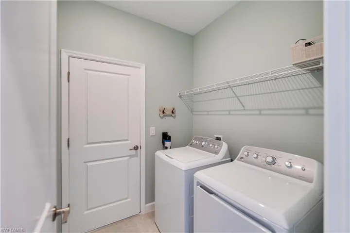 Washroom featuring light tile patterned flooring and washer and dryer