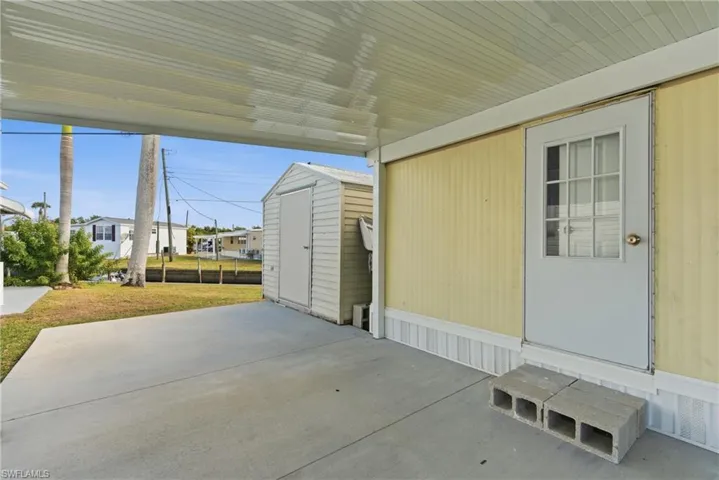 View of side door from second bedroom and a storage shed
