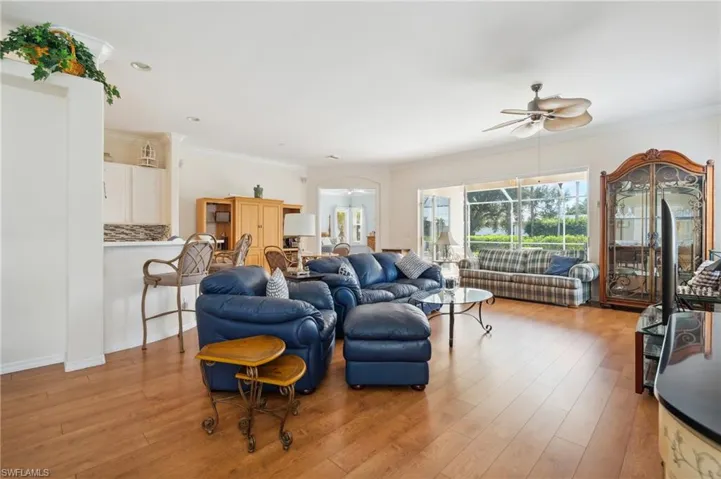 Living room featuring ceiling fan, wood-type flooring, and ornamental molding