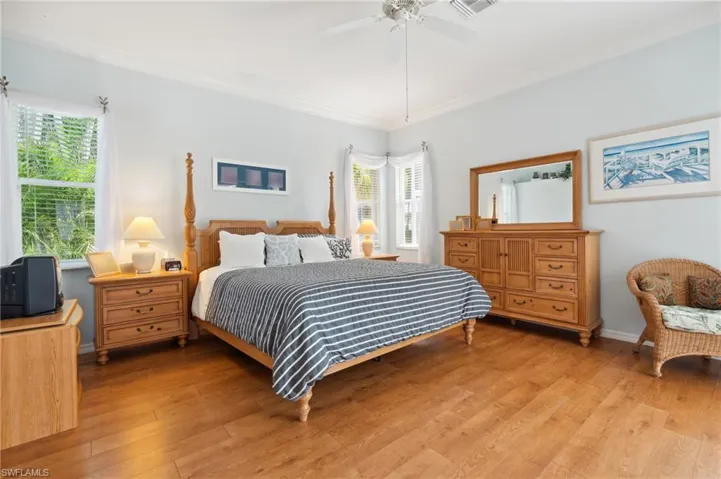 Bedroom with ceiling fan, ornamental molding, and light wood-type flooring