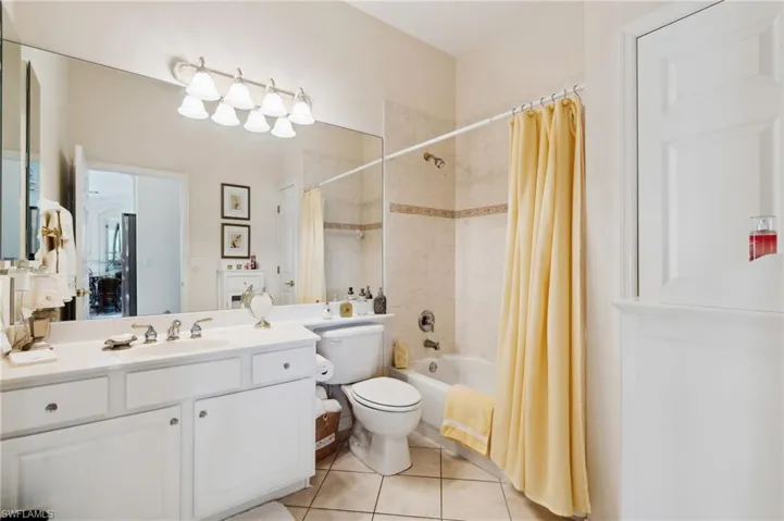 Full bathroom with vanity, toilet, tile patterned flooring, and shower / bath combo with shower curtain