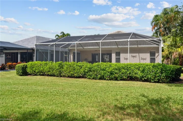 Back of house featuring glass enclosure and a yard