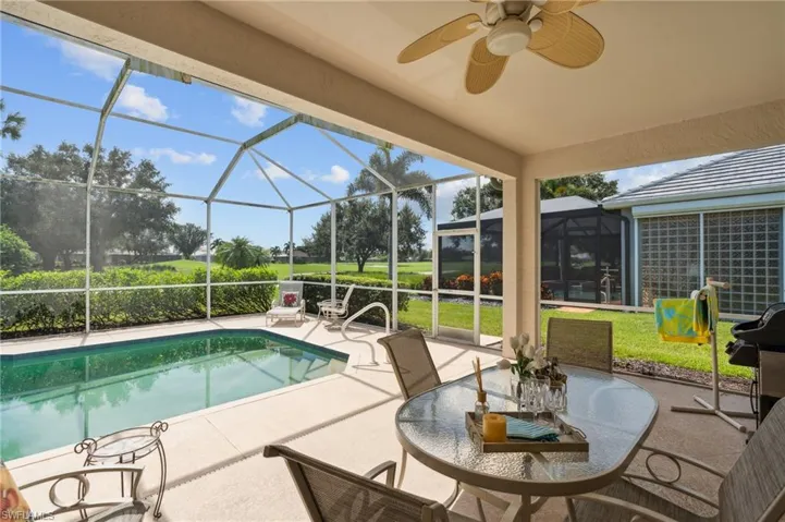 View of swimming pool with glass enclosure, a patio area, and ceiling fan