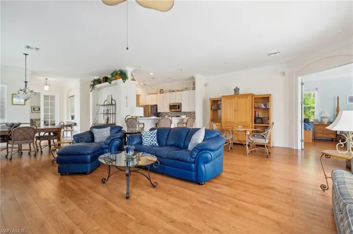 Living room with light wood-type flooring, crown molding, and ceiling fan