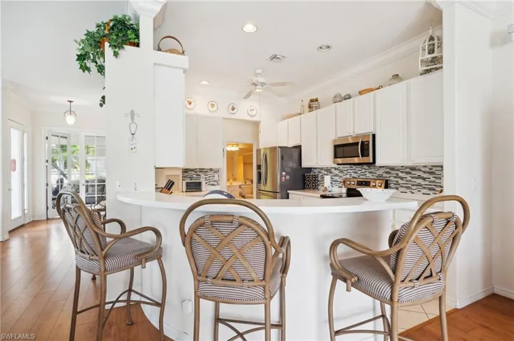 Kitchen featuring light hardwood / wood-style flooring, appliances with stainless steel finishes, backsplash, and ceiling fan